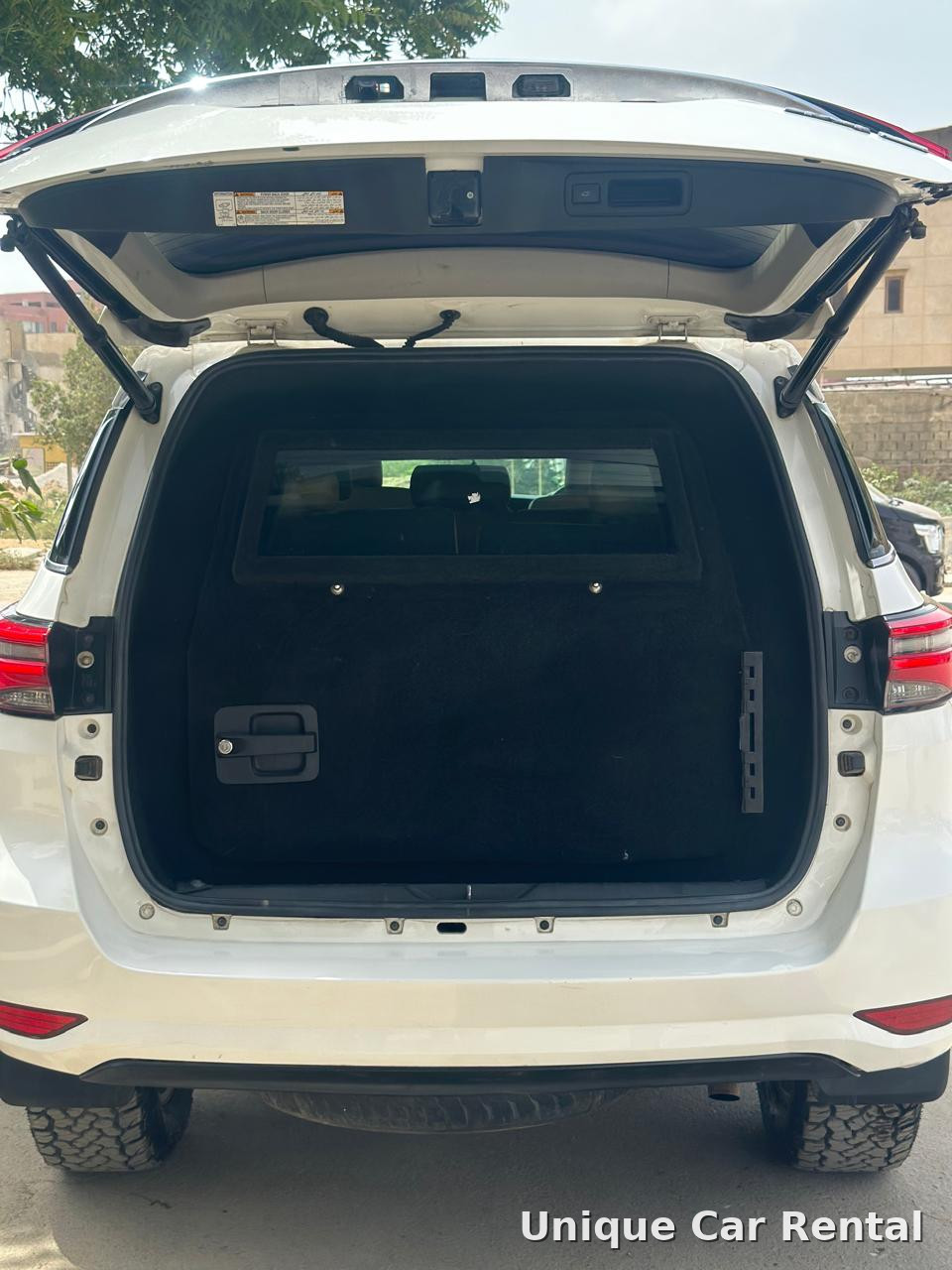 White armored Toyota Fortuner with rear door open showing the protected compartment