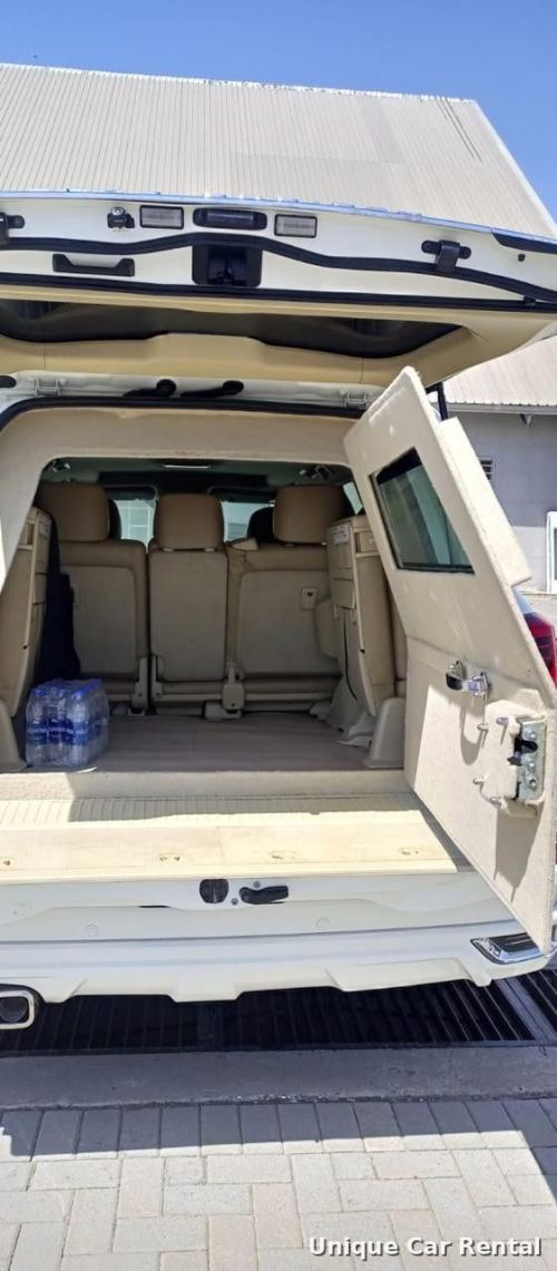 White armored Toyota Land Cruiser 200 with rear door open showing interior