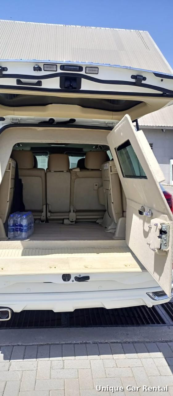 White armored Toyota Land Cruiser 200 with rear door open showing interior