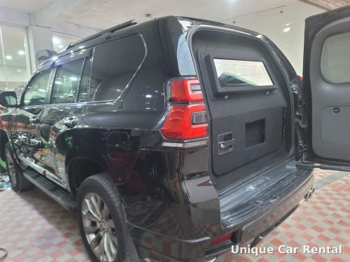 Black bulletproof Toyota Prado with armored rear door open showing ballistic glass window