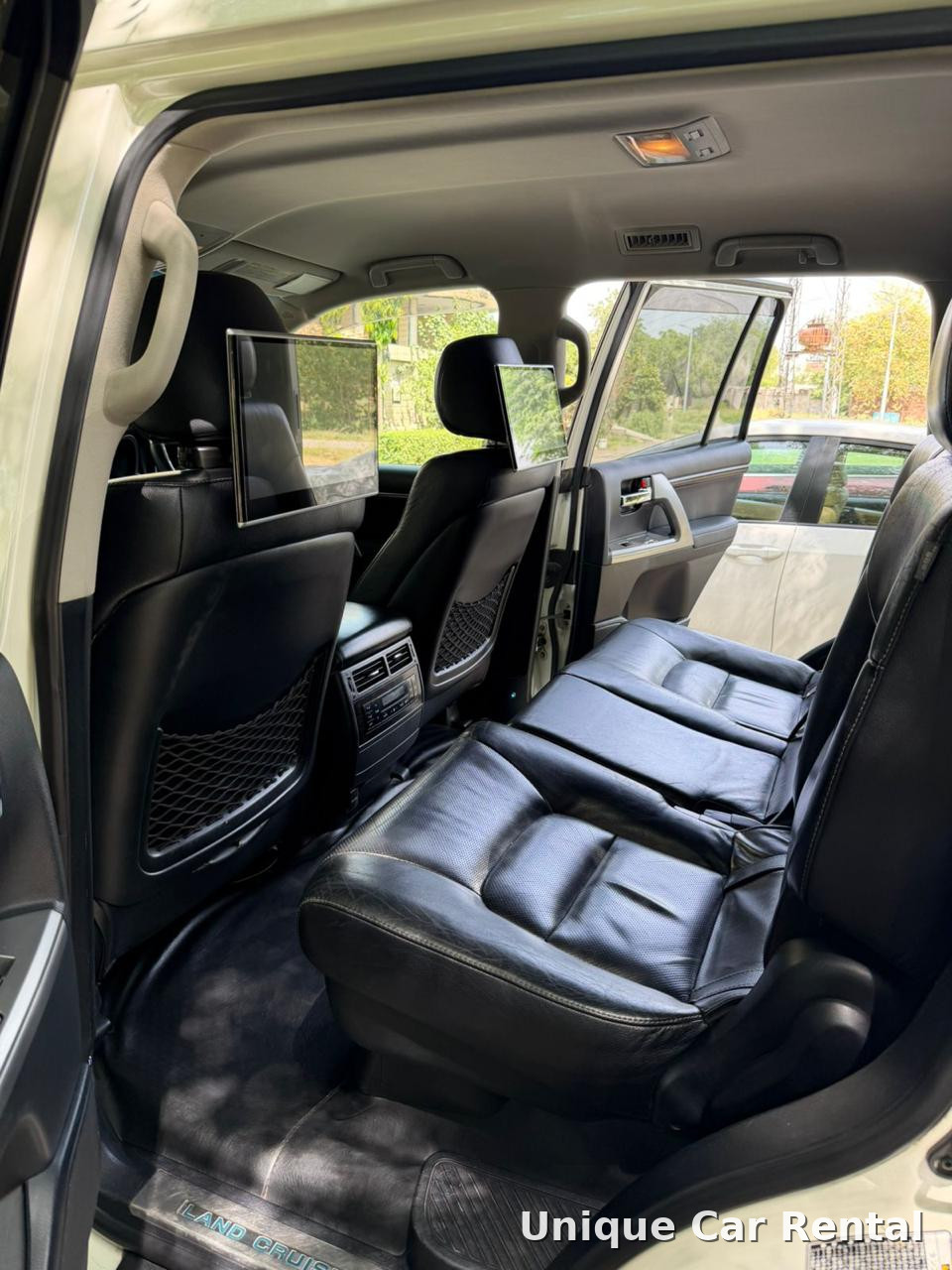 Rear black leather seats with entertainment screens inside a Toyota Land Cruiser 200